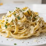 Creamy garlic pasta served on a white plate with Parmesan cheese, fresh parsley, and a rich homemade garlic cream sauce.