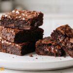 Homemade fudgy brownies with crackly tops and rich chocolate centers served on a white plate.